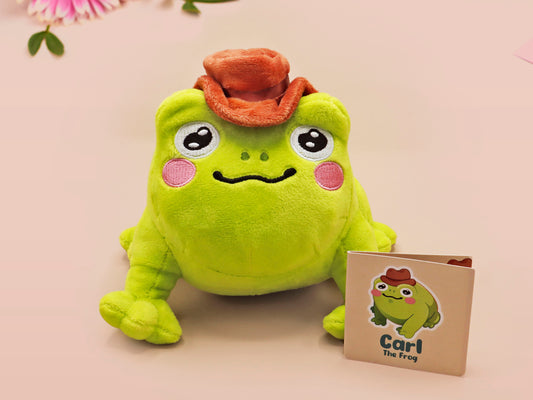 An adorable green frog plushie toy with cute embroidered eyes and facial expression, wearing a cowboy hat with a brown ribbon, and a hang tag describing the frog as Carl.