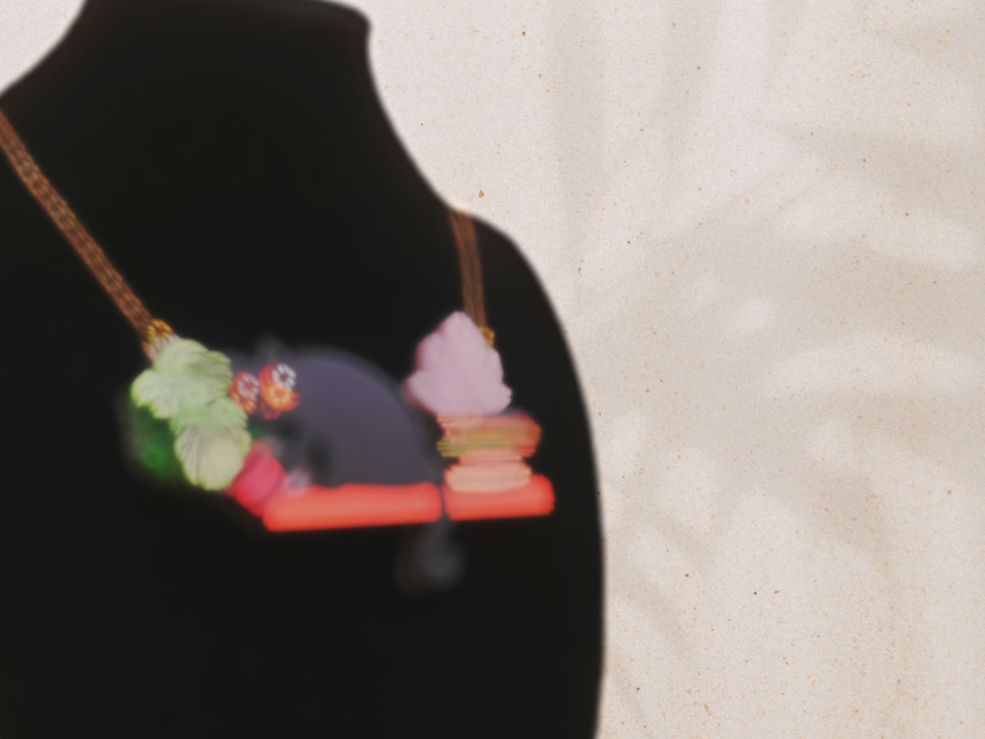 Video of front and back of mixed material handmade necklace of chibi cartoon cat sat on a witch's book shelf with pearlescent crystal. knocking a plant pot of the edge, with a gold chain and black gift box with a blue familiars collection gift sleeve. on black bust.